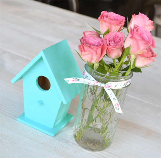 For a simple spring centerpiece, paint a wooden birdhouse and pair with fresh flowers.